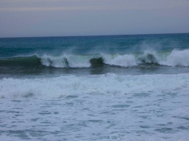 büyük dalgalar kum ve sahil kayalara çarpıyor