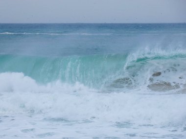büyük dalgalar kum ve sahil kayalara çarpıyor