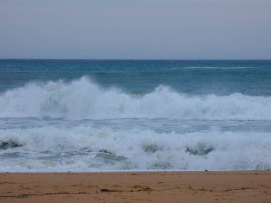 büyük dalgalar kum ve sahil kayalara çarpıyor