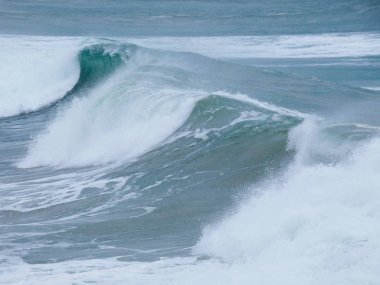 büyük dalgalar kum ve sahil kayalara çarpıyor