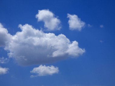 Mavi gökyüzünün üzerindeki bulutlar kaprisli şekiller oluşturuyor