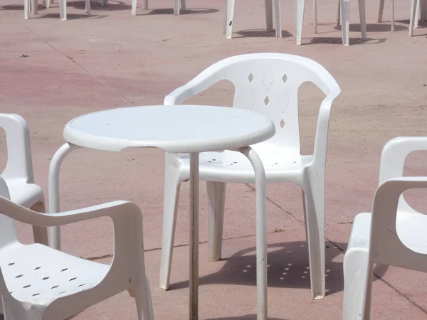 Beyaz plastik masalar, sandalyeler, teraslar, bahçeler.