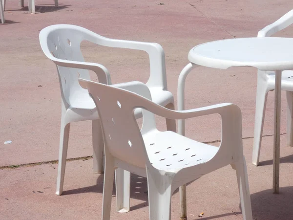 Beyaz plastik masalar, sandalyeler, teraslar, bahçeler.