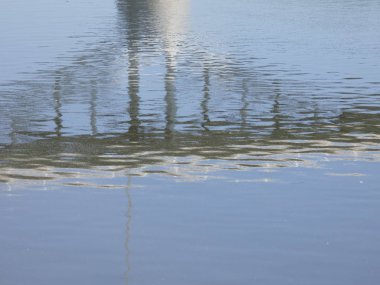 Rio baharda bir köprüyü geçerken, yansımaları ile mavi su gökyüzünün yansıması nedeniyle. Llobregat Nehri, Sant Feliu de Llobregat'tan geçerken Akdeniz'in ağzına çok yakın