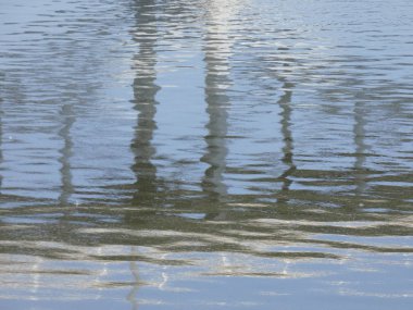 Rio baharda bir köprüyü geçerken, yansımaları ile mavi su gökyüzünün yansıması nedeniyle. Llobregat Nehri, Sant Feliu de Llobregat'tan geçerken Akdeniz'in ağzına çok yakın