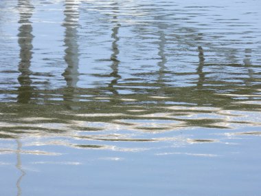Rio baharda bir köprüyü geçerken, yansımaları ile mavi su gökyüzünün yansıması nedeniyle. Llobregat Nehri, Sant Feliu de Llobregat'tan geçerken Akdeniz'in ağzına çok yakın