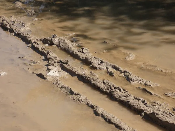 Wheel marks in a puddle of water filled with mud. Ruts, marks and signs of a car passing through a puddle of water and lots of mud