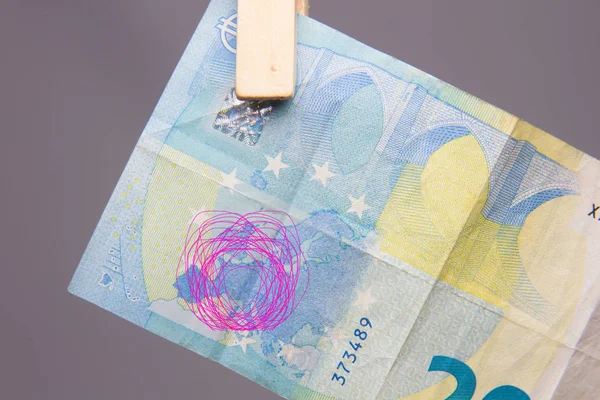 Money in euros, 20 euro bill lying on a rope and caught with a pair of tweezers. Money is used to buy and to invest, it is the product used by banks to leave customers and apply a percentage that are the benefits