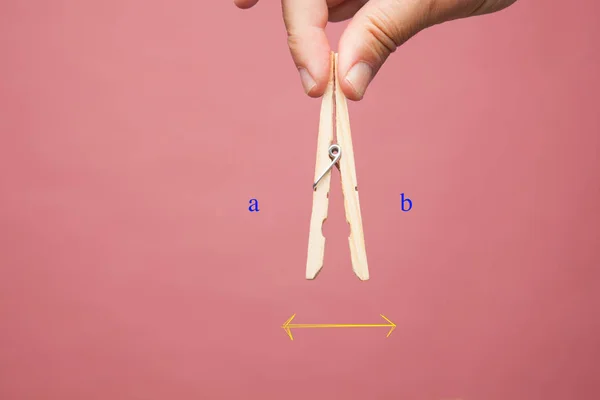 Elbise mandal, pembe arka planda bir yetişkin kişinin elinin parmaklarında ahşap clothespins