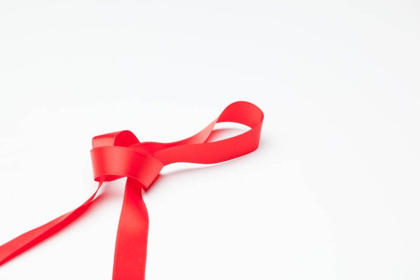 красная лента, чтобы сделать декоративные галстуки в рождественские подарки, подарки ко дню рождения, юбилеи, подарки в целом; красная лента на белом фоне
