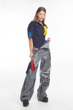 Güzel, seksi, şehvetli kız beyaz arka plan üzerinde fütüristik kentsel giysiler ile poz