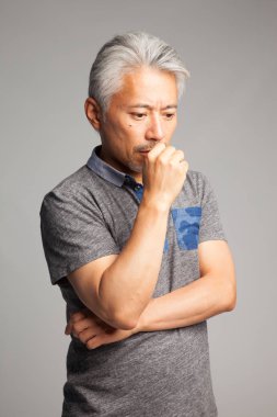 Asya kökenli orta yaşlı bir adam, özellikle Japon, kolları ve elleri ile jest ve ifadeler yapıyor.