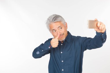 Elinde akıllı telefon olan orta yaşlı bir adam iletişim kuruyor ve selfie çekiyor. Telefonuyla fotoğraf çeken bir adam.