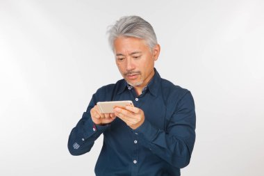 Elinde akıllı telefon olan orta yaşlı bir adam iletişim kuruyor ve selfie çekiyor. Telefonuyla fotoğraf çeken bir adam.