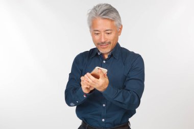 Elinde akıllı telefon olan orta yaşlı bir adam iletişim kuruyor ve selfie çekiyor. Telefonuyla fotoğraf çeken bir adam.