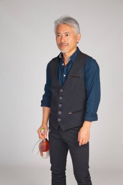 Asya kökenli, Japon kökenli orta yaşlı bir adam, bir şişe şampanya ya da gül şarabı, alkollü içecek, parti ya da bir şişe pembe şampanya ile yıldönümü kutlaması.