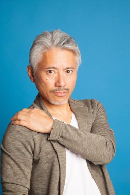 Japon kökenli orta yaşlı bir adam, elleri ve kollarıyla el kol hareketi yapıyor, etkileyici bir adam..