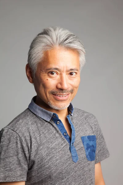 Asya kökenli orta yaşlı bir adam, özellikle Japon, kolları ve elleri ile jest ve ifadeler yapıyor.