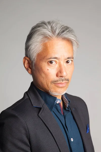 Middle-aged man of Japanese and Asian origin, studio portrait with intriguing look