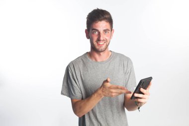 Genç bir çocuk akıllı telefonuyla özçekim yapıyor, surat ve yüz ifadeleri yapıyor.