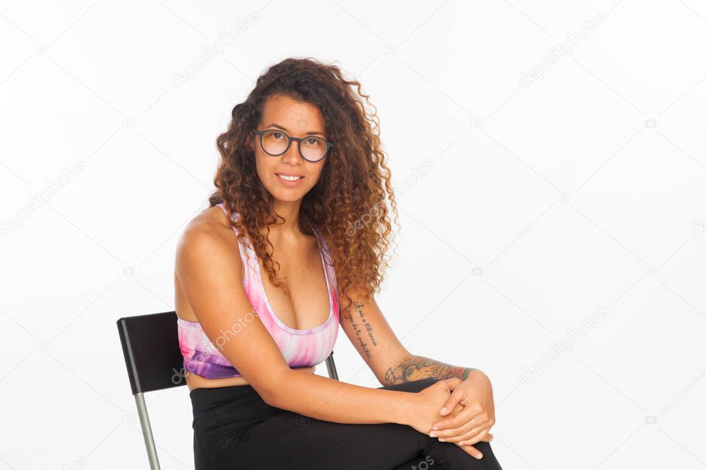 Pretty and sporty girl sitting and relaxing on a simple chair, white background