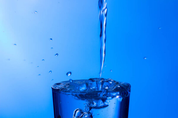 Чистая, питьевая вода попадает в прозрачный стакан, здоровая, здоровая, пресная вода без запаха и вкуса. Всплеск капель воды, брызгающихся на поверхность. Реактивный поток воды в стекло
