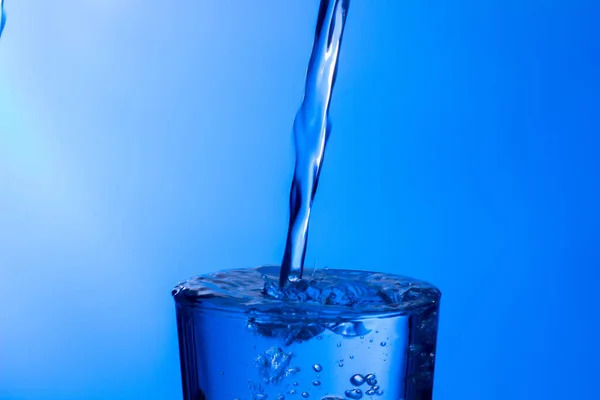 澄んだ飲料水は 澄んだガラス 健康的で健全な 臭いや味のない新鮮な水に落ちます 水のスプラッシュは 表面に飛び散った ガラスに入った水のジェット — ストック写真