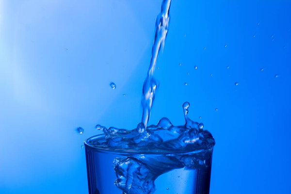 Чистая, питьевая вода попадает в прозрачный стакан, здоровая, здоровая, пресная вода без запаха и вкуса. Всплеск капель воды, брызгающихся на поверхность. Реактивный поток воды в стекло
