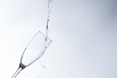 Temiz, içme suyu temiz bir bardağa dökülüyor, sağlıklı, sağlıklı, temiz, kokusuz ve tatsız bir su. Yüzeye su damlaları sıçrıyor. Jet su bardağa giriyor