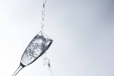 Temiz, içme suyu temiz bir bardağa dökülüyor, sağlıklı, sağlıklı, temiz, kokusuz ve tatsız bir su. Yüzeye su damlaları sıçrıyor. Jet su bardağa giriyor