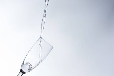 Temiz, içme suyu temiz bir bardağa dökülüyor, sağlıklı, sağlıklı, temiz, kokusuz ve tatsız bir su. Yüzeye su damlaları sıçrıyor. Jet su bardağa giriyor