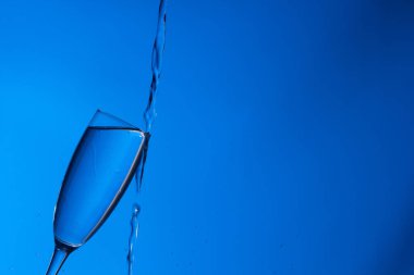 Temiz, içme suyu temiz bir bardağa dökülüyor, sağlıklı, sağlıklı, temiz, kokusuz ve tatsız bir su. Yüzeye su damlaları sıçrıyor. Jet su bardağa giriyor