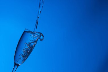 Temiz, içme suyu temiz bir bardağa dökülüyor, sağlıklı, sağlıklı, temiz, kokusuz ve tatsız bir su. Yüzeye su damlaları sıçrıyor. Jet su bardağa giriyor