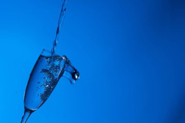 Temiz, içme suyu temiz bir bardağa dökülüyor, sağlıklı, sağlıklı, temiz, kokusuz ve tatsız bir su. Yüzeye su damlaları sıçrıyor. Jet su bardağa giriyor