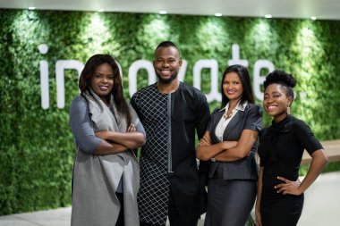 Çevre dostu modern ofis alanında yan yana dururken gülümseyen çeşitli Afrikalı iş adamlarının portresi.