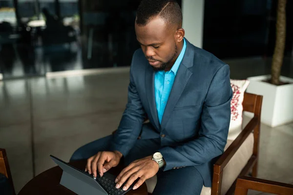 사무실 로비에 책상에 디지털 태블릿으로 일하는 아프리카 사업가에게 초점을 맞추다 — 스톡 사진