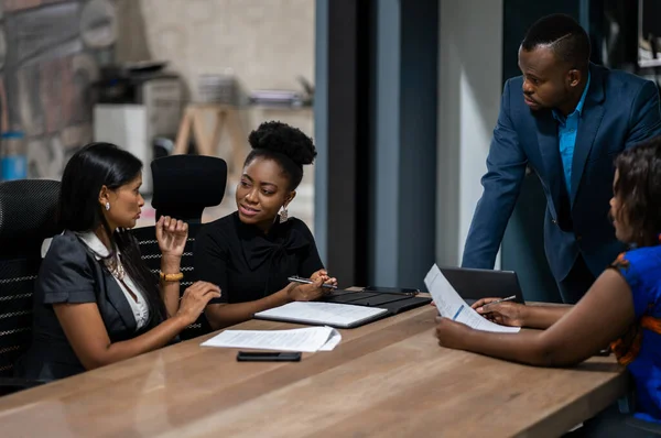 非洲商人与各种各样的女同事交谈 同时在一个办公室会议室的桌旁聚会 — 图库照片