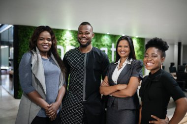 Bir grup gülümseyen Afrikalı iş adamının portresi modern bir ofisin lobisinde yan yana duruyor.