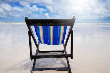 Mavi ahşap plaj sandalyesi beyaz bulutlar ve yaz sezonu gelince mavi gökyüzü ile sahilde