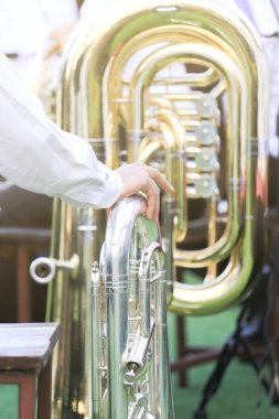 Euphonium, silver brass music instrument and man's hand touching between waiting for rehearsal classical music clipart