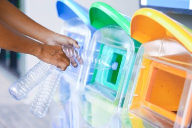 Erkek eli boş plastik şişe yeşil dünya için çevre ve geri dönüşüm fikir olarak yeşil çöp kutusu koyarak.