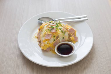 Pirinç ve sos beyaz seramik tabak ve kaşık ve çatal kesilerek domuz pastırmalı omlet