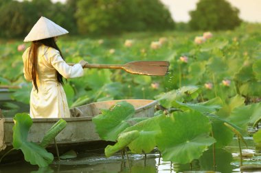 Ahşap antik tekne ile lotus gölet ao dai traditonal vietnamlı sarı ve beyaz elbise Vietnamlı kadın.
