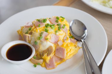 Pirinç ve sos beyaz seramik tabak ve kaşık ve çatal kesilerek domuz pastırmalı omlet