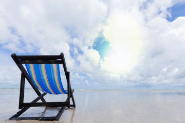 Mavi ahşap plaj sandalyesi beyaz bulutlar ve yaz sezonu gelince mavi gökyüzü ile sahilde