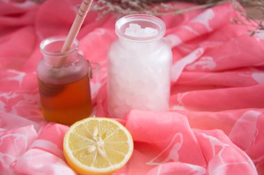 Bal kavanozve tuz ve çiçek arka plan, pembe bez ve sağlıklı ve spa konsepti için sesi ile taze kesilmiş limon