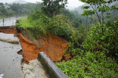Şiddetli yağmurların yol açtığı heyelan, bozuk yol asfaltına neden olur. Sokakta yıkılmış çimento. Toprak kaymasından çıkan çatlak yol sağanak yağış yüzünden mahvoldu.