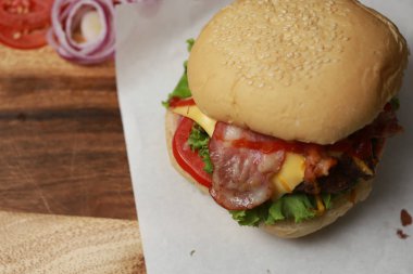 Koyu tonda sığır burger, ahşap tabakta loş ışık ve arka planda koyu renk