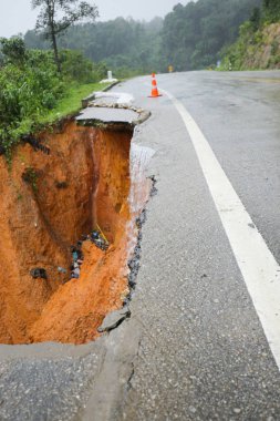 Şiddetli yağmurların yol açtığı heyelan, bozuk yol asfaltına neden olur. Sokakta yıkılmış çimento. Toprak kaymasından çıkan çatlak yol sağanak yağış yüzünden mahvoldu.