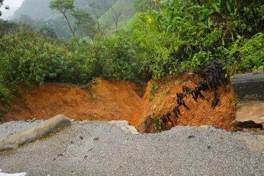 Şiddetli yağmurların yol açtığı heyelan, bozuk yol asfaltına neden olur. Sokakta yıkılmış çimento. Toprak kaymasından çıkan çatlak yol sağanak yağış yüzünden mahvoldu.